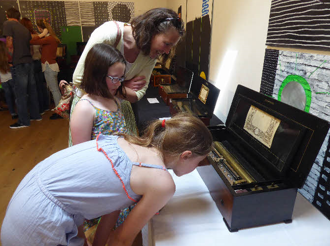 Young people inspecting a musical box at a Society exhibition